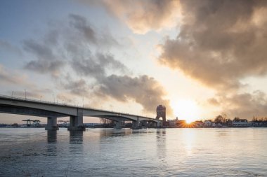 Eski tarihi bir şehir kapısından bir yol ya da otoyol geçiyor. Solucanlar, Almanya yakınlarındaki Ren nehrinde akşam üstü gün batımı