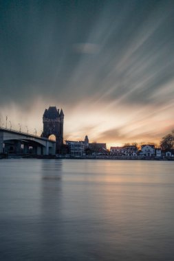 Eski tarihi bir şehir kapısından bir yol ya da otoyol geçiyor. Solucanlar, Almanya yakınlarındaki Ren nehrinde akşam üstü gün batımı