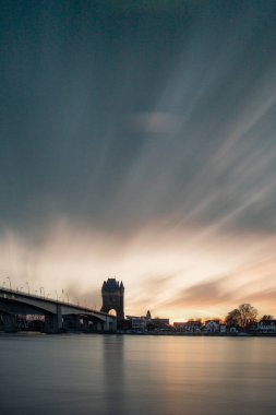 Eski tarihi bir şehir kapısından bir yol ya da otoyol geçiyor. Solucanlar, Almanya yakınlarındaki Ren nehrinde akşam üstü gün batımı