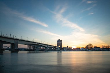 Eski tarihi bir şehir kapısından bir yol ya da otoyol geçiyor. Solucanlar, Almanya yakınlarındaki Ren nehrinde akşam üstü gün batımı