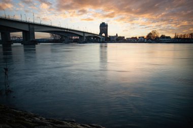 Eski tarihi bir şehir kapısından bir yol ya da otoyol geçiyor. Solucanlar, Almanya yakınlarındaki Ren nehrinde akşam üstü gün batımı