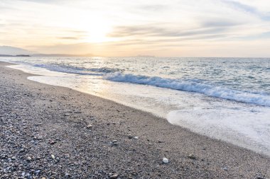 Gün batımında kumlu ve çakıl taşı plajı olan güzel bir sahil şeridi. Platanes Beach, Rethymno, Girit, Yunanistan 'ın turizm ve otel bölgesinde güzel gökyüzü renklendirmesi