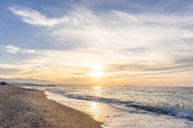 Gün batımında kumlu ve çakıl taşı plajı olan güzel bir sahil şeridi. Platanes Beach, Rethymno, Girit, Yunanistan 'ın turizm ve otel bölgesinde güzel gökyüzü renklendirmesi