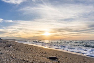 Gün batımında kumlu ve çakıl taşı plajı olan güzel bir sahil şeridi. Platanes Beach, Rethymno, Girit, Yunanistan 'ın turizm ve otel bölgesinde güzel gökyüzü renklendirmesi
