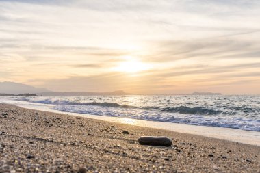 Gün batımında kumlu ve çakıl taşı plajı olan güzel bir sahil şeridi. Platanes Beach, Rethymno, Girit, Yunanistan 'ın turizm ve otel bölgesinde güzel gökyüzü renklendirmesi