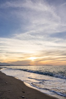 Gün batımında kumlu ve çakıl taşı plajı olan güzel bir sahil şeridi. Platanes Beach, Rethymno, Girit, Yunanistan 'ın turizm ve otel bölgesinde güzel gökyüzü renklendirmesi
