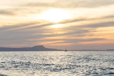 Gün batımında kumlu ve çakıl taşı plajı olan güzel bir sahil şeridi. Platanes Beach, Rethymno, Girit, Yunanistan 'ın turizm ve otel bölgesinde güzel gökyüzü renklendirmesi