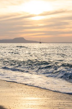 Gün batımında kumlu ve çakıl taşı plajı olan güzel bir sahil şeridi. Platanes Beach, Rethymno, Girit, Yunanistan 'ın turizm ve otel bölgesinde güzel gökyüzü renklendirmesi
