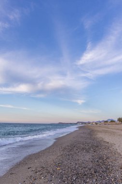 Gün batımında kumlu ve çakıl taşı plajı olan güzel bir sahil şeridi. Platanes Beach, Rethymno, Girit, Yunanistan 'ın turizm ve otel bölgesinde güzel gökyüzü renklendirmesi