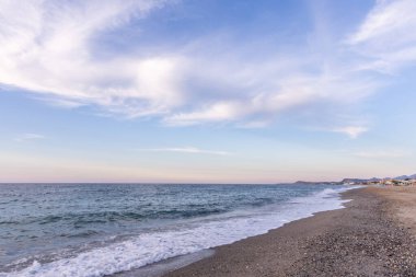 Gün batımında kumlu ve çakıl taşı plajı olan güzel bir sahil şeridi. Platanes Beach, Rethymno, Girit, Yunanistan 'ın turizm ve otel bölgesinde güzel gökyüzü renklendirmesi