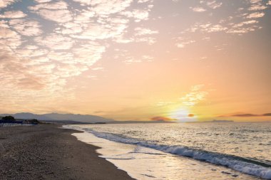 Gün batımında kumlu ve çakıl taşı plajı olan güzel bir sahil şeridi. Platanes Beach, Rethymno, Girit, Yunanistan 'ın turizm ve otel bölgesinde güzel gökyüzü renklendirmesi