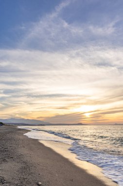 Gün batımında kumlu ve çakıl taşı plajı olan güzel bir sahil şeridi. Platanes Beach, Rethymno, Girit, Yunanistan 'ın turizm ve otel bölgesinde güzel gökyüzü renklendirmesi