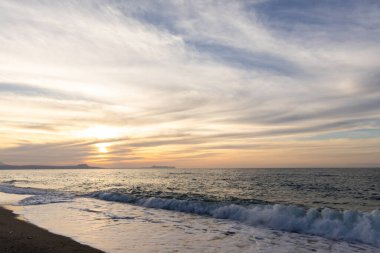 Gün batımında kumlu ve çakıl taşı plajı olan güzel bir sahil şeridi. Platanes Beach, Rethymno, Girit, Yunanistan 'ın turizm ve otel bölgesinde güzel gökyüzü renklendirmesi