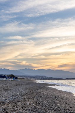 Gün batımında kumlu ve çakıl taşı plajı olan güzel bir sahil şeridi. Platanes Beach, Rethymno, Girit, Yunanistan 'ın turizm ve otel bölgesinde güzel gökyüzü renklendirmesi