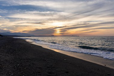 Gün batımında kumlu ve çakıl taşı plajı olan güzel bir sahil şeridi. Platanes Beach, Rethymno, Girit, Yunanistan 'ın turizm ve otel bölgesinde güzel gökyüzü renklendirmesi
