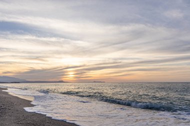 Gün batımında kumlu ve çakıl taşı plajı olan güzel bir sahil şeridi. Platanes Beach, Rethymno, Girit, Yunanistan 'ın turizm ve otel bölgesinde güzel gökyüzü renklendirmesi