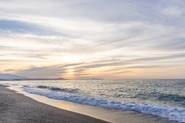 Gün batımında kumlu ve çakıl taşı plajı olan güzel bir sahil şeridi. Platanes Beach, Rethymno, Girit, Yunanistan 'ın turizm ve otel bölgesinde güzel gökyüzü renklendirmesi