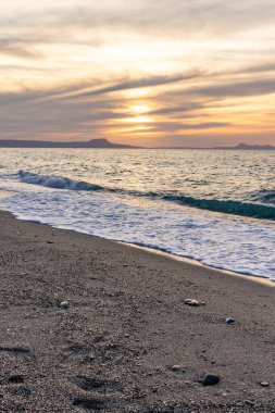 Gün batımında kumlu ve çakıl taşı plajı olan güzel bir sahil şeridi. Platanes Beach, Rethymno, Girit, Yunanistan 'ın turizm ve otel bölgesinde güzel gökyüzü renklendirmesi