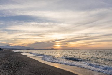 Gün batımında kumlu ve çakıl taşı plajı olan güzel bir sahil şeridi. Platanes Beach, Rethymno, Girit, Yunanistan 'ın turizm ve otel bölgesinde güzel gökyüzü renklendirmesi