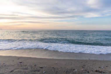Gün batımında kumlu ve çakıl taşı plajı olan güzel bir sahil şeridi. Platanes Beach, Rethymno, Girit, Yunanistan 'ın turizm ve otel bölgesinde güzel gökyüzü renklendirmesi