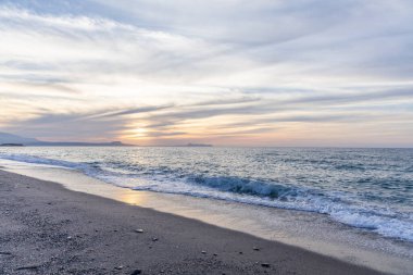 Gün batımında kumlu ve çakıl taşı plajı olan güzel bir sahil şeridi. Platanes Beach, Rethymno, Girit, Yunanistan 'ın turizm ve otel bölgesinde güzel gökyüzü renklendirmesi