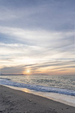 Gün batımında kumlu ve çakıl taşı plajı olan güzel bir sahil şeridi. Platanes Beach, Rethymno, Girit, Yunanistan 'ın turizm ve otel bölgesinde güzel gökyüzü renklendirmesi