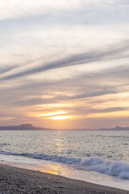 Gün batımında kumlu ve çakıl taşı plajı olan güzel bir sahil şeridi. Platanes Beach, Rethymno, Girit, Yunanistan 'ın turizm ve otel bölgesinde güzel gökyüzü renklendirmesi