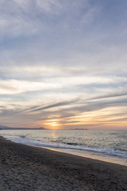 Gün batımında kumlu ve çakıl taşı plajı olan güzel bir sahil şeridi. Platanes Beach, Rethymno, Girit, Yunanistan 'ın turizm ve otel bölgesinde güzel gökyüzü renklendirmesi