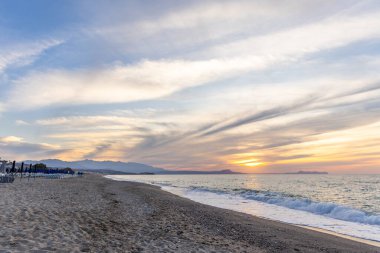 Gün batımında kumlu ve çakıl taşı plajı olan güzel bir sahil şeridi. Platanes Beach, Rethymno, Girit, Yunanistan 'ın turizm ve otel bölgesinde güzel gökyüzü renklendirmesi
