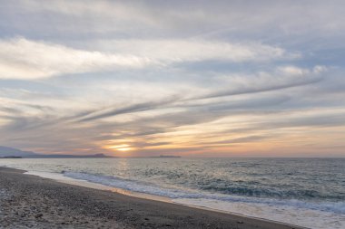 Gün batımında kumlu ve çakıl taşı plajı olan güzel bir sahil şeridi. Platanes Beach, Rethymno, Girit, Yunanistan 'ın turizm ve otel bölgesinde güzel gökyüzü renklendirmesi