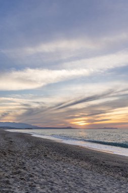 Gün batımında kumlu ve çakıl taşı plajı olan güzel bir sahil şeridi. Platanes Beach, Rethymno, Girit, Yunanistan 'ın turizm ve otel bölgesinde güzel gökyüzü renklendirmesi