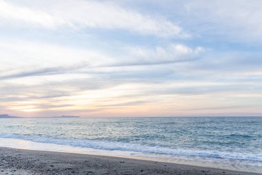 Gün batımında kumlu ve çakıl taşı plajı olan güzel bir sahil şeridi. Platanes Beach, Rethymno, Girit, Yunanistan 'ın turizm ve otel bölgesinde güzel gökyüzü renklendirmesi