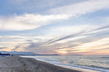 Gün batımında kumlu ve çakıl taşı plajı olan güzel bir sahil şeridi. Platanes Beach, Rethymno, Girit, Yunanistan 'ın turizm ve otel bölgesinde güzel gökyüzü renklendirmesi