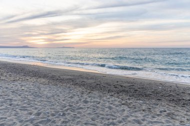 Gün batımında kumlu ve çakıl taşı plajı olan güzel bir sahil şeridi. Platanes Beach, Rethymno, Girit, Yunanistan 'ın turizm ve otel bölgesinde güzel gökyüzü renklendirmesi