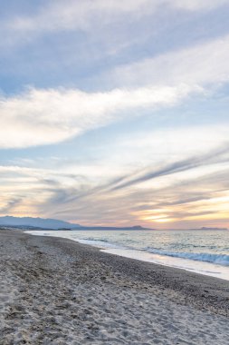 Gün batımında kumlu ve çakıl taşı plajı olan güzel bir sahil şeridi. Platanes Beach, Rethymno, Girit, Yunanistan 'ın turizm ve otel bölgesinde güzel gökyüzü renklendirmesi