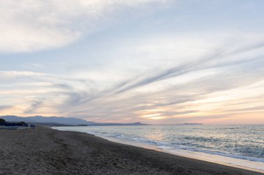 Gün batımında kumlu ve çakıl taşı plajı olan güzel bir sahil şeridi. Platanes Beach, Rethymno, Girit, Yunanistan 'ın turizm ve otel bölgesinde güzel gökyüzü renklendirmesi