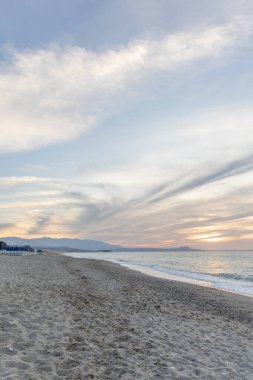 Gün batımında kumlu ve çakıl taşı plajı olan güzel bir sahil şeridi. Platanes Beach, Rethymno, Girit, Yunanistan 'ın turizm ve otel bölgesinde güzel gökyüzü renklendirmesi