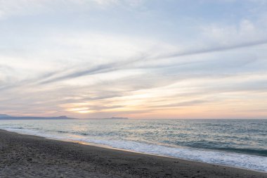 Gün batımında kumlu ve çakıl taşı plajı olan güzel bir sahil şeridi. Platanes Beach, Rethymno, Girit, Yunanistan 'ın turizm ve otel bölgesinde güzel gökyüzü renklendirmesi