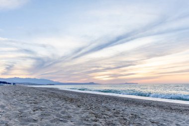 Gün batımında kumlu ve çakıl taşı plajı olan güzel bir sahil şeridi. Platanes Beach, Rethymno, Girit, Yunanistan 'ın turizm ve otel bölgesinde güzel gökyüzü renklendirmesi