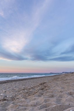 Gün batımında kumlu ve çakıl taşı plajı olan güzel bir sahil şeridi. Platanes Beach, Rethymno, Girit, Yunanistan 'ın turizm ve otel bölgesinde güzel gökyüzü renklendirmesi