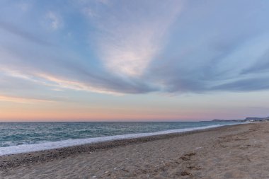 Gün batımında kumlu ve çakıl taşı plajı olan güzel bir sahil şeridi. Platanes Beach, Rethymno, Girit, Yunanistan 'ın turizm ve otel bölgesinde güzel gökyüzü renklendirmesi