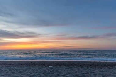 Gün batımında kumlu ve çakıl taşı plajı olan güzel bir sahil şeridi. Platanes Beach, Rethymno, Girit, Yunanistan 'ın turizm ve otel bölgesinde güzel gökyüzü renklendirmesi