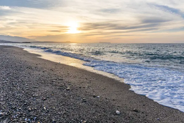 Gün batımında kumlu ve çakıl taşı plajı olan güzel bir sahil şeridi. Platanes Beach, Rethymno, Girit, Yunanistan 'ın turizm ve otel bölgesinde güzel gökyüzü renklendirmesi