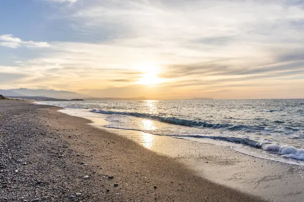 Gün batımında kumlu ve çakıl taşı plajı olan güzel bir sahil şeridi. Platanes Beach, Rethymno, Girit, Yunanistan 'ın turizm ve otel bölgesinde güzel gökyüzü renklendirmesi