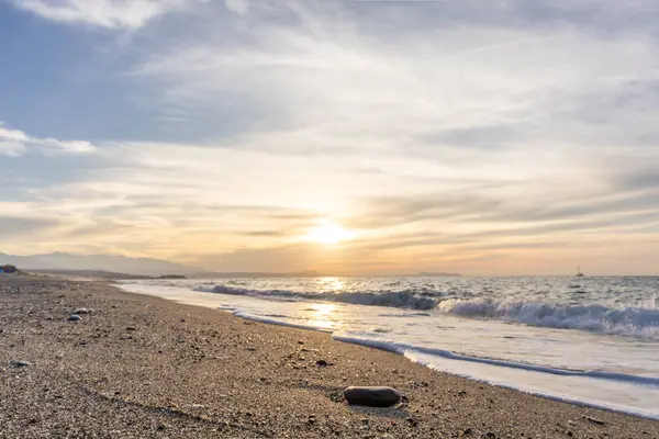 Gün batımında kumlu ve çakıl taşı plajı olan güzel bir sahil şeridi. Platanes Beach, Rethymno, Girit, Yunanistan 'ın turizm ve otel bölgesinde güzel gökyüzü renklendirmesi