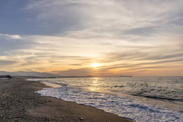 Gün batımında kumlu ve çakıl taşı plajı olan güzel bir sahil şeridi. Platanes Beach, Rethymno, Girit, Yunanistan 'ın turizm ve otel bölgesinde güzel gökyüzü renklendirmesi