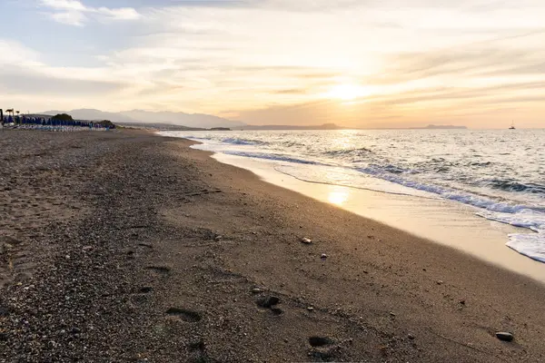 Gün batımında kumlu ve çakıl taşı plajı olan güzel bir sahil şeridi. Platanes Beach, Rethymno, Girit, Yunanistan 'ın turizm ve otel bölgesinde güzel gökyüzü renklendirmesi