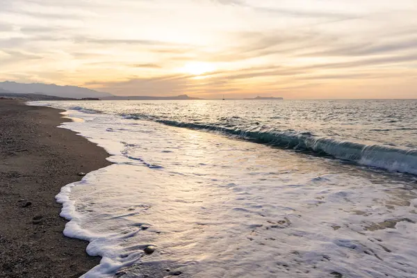 Gün batımında kumlu ve çakıl taşı plajı olan güzel bir sahil şeridi. Platanes Beach, Rethymno, Girit, Yunanistan 'ın turizm ve otel bölgesinde güzel gökyüzü renklendirmesi