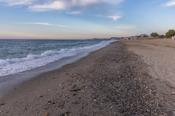 Gün batımında kumlu ve çakıl taşı plajı olan güzel bir sahil şeridi. Platanes Beach, Rethymno, Girit, Yunanistan 'ın turizm ve otel bölgesinde güzel gökyüzü renklendirmesi