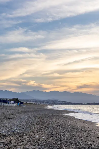 Gün batımında kumlu ve çakıl taşı plajı olan güzel bir sahil şeridi. Platanes Beach, Rethymno, Girit, Yunanistan 'ın turizm ve otel bölgesinde güzel gökyüzü renklendirmesi